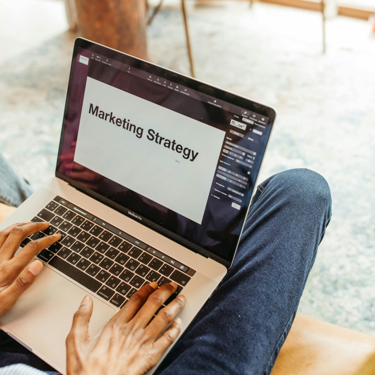 Close-up of hands using a laptop displaying a marketing strategy presentation indoors.